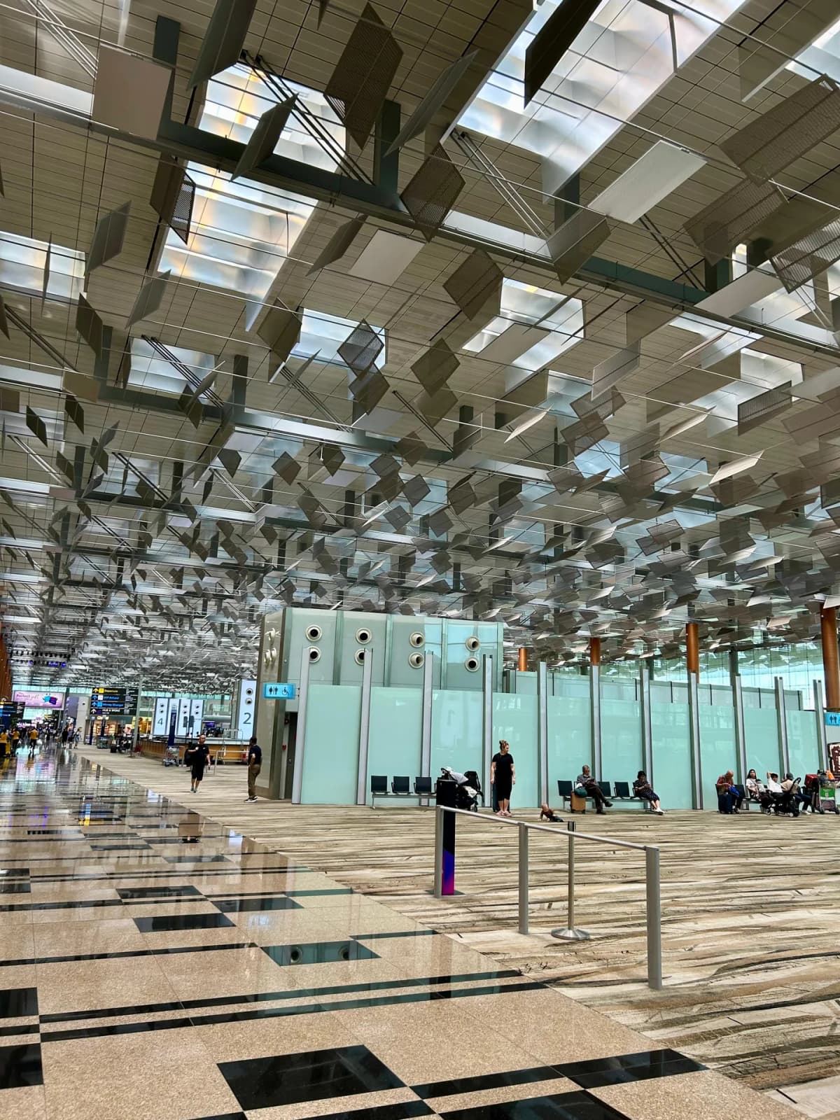 Departure hall inside a Changi Airport terminal with its sculptural suspended metal ceiling and polished marble floor